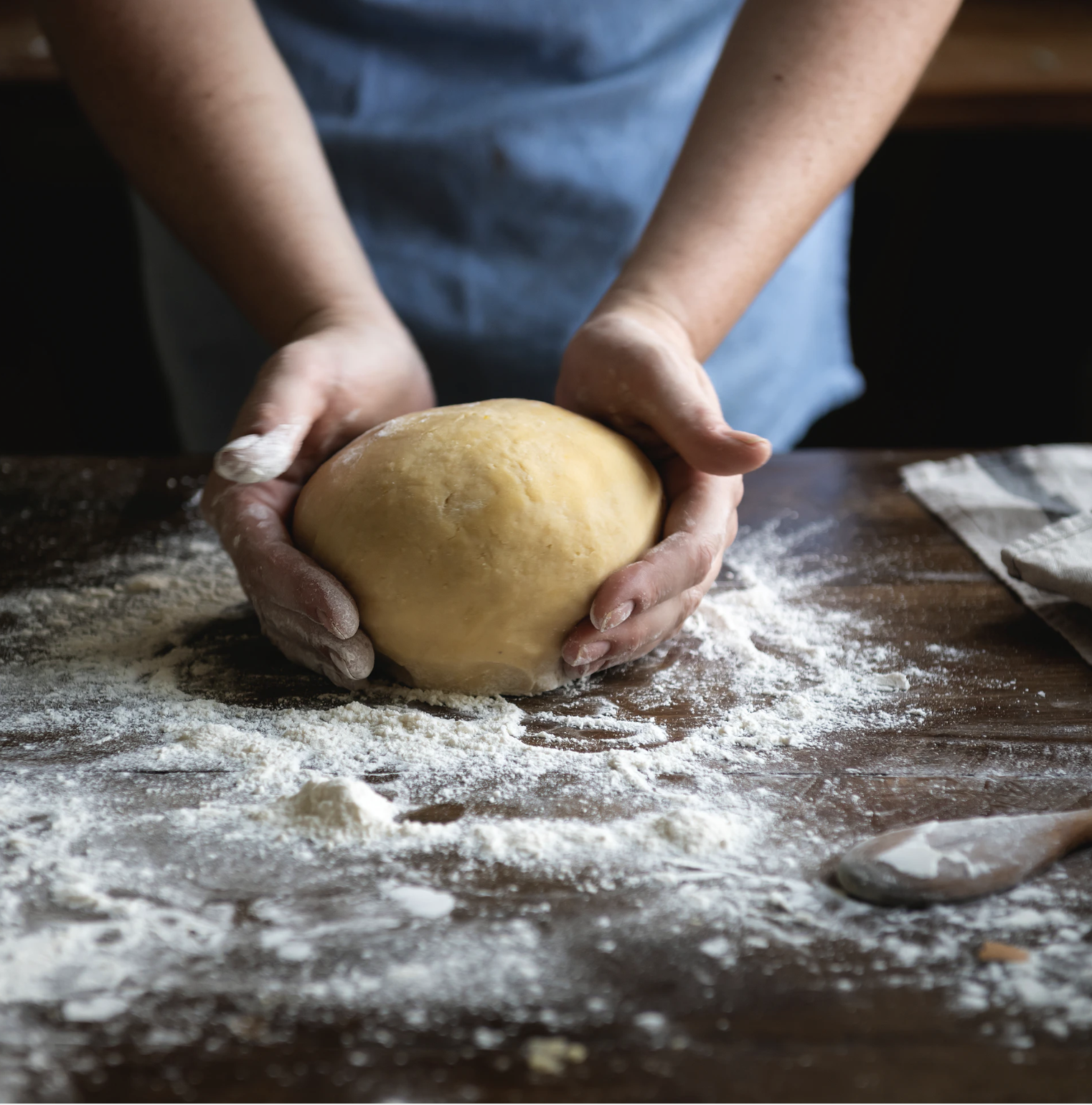 Mani che lavorano un impasto di ravioli su una spianatoia